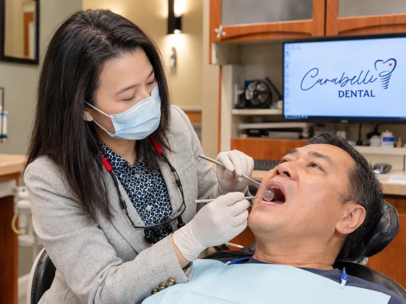 A dental professional assessing the gumline with a dental mirror during a gum health examination.
